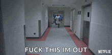 a person is walking down a hospital hallway with the words " fuck this im out " written on it .