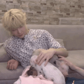 a woman in a leopard print shirt is petting a pig