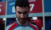 a man with a beard is standing in a locker room with the number 87 on the wall
