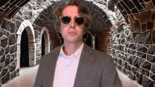a man in a suit and sunglasses stands in a tunnel