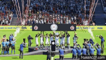 a group of soccer players are standing on a podium in front of a crowd .