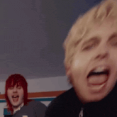 a man with red hair is standing next to another man with blonde hair making a funny face .