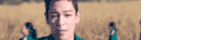 a blurry picture of a man standing in a field with a group of people in the background .