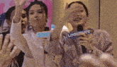 a woman is holding a microphone and waving at a crowd .