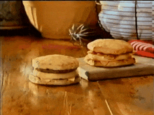 two sandwiches are sitting on a wooden table next to each other