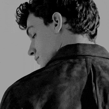 a black and white photo of a young man in a leather jacket .
