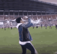 a man is standing on a soccer field holding a bottle of water in his hand .