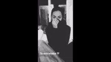a woman is covering her face with her hand in a black and white photo .