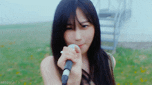 a woman is singing into a microphone while standing in a field .