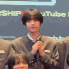 a group of people are clapping their hands together in front of a sign that says youtube .