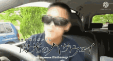 a man wearing sunglasses is driving a car with chinese writing