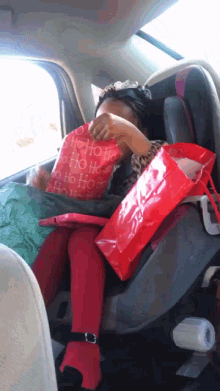 a child is sitting in a car seat with a red bag that says ho ho ho