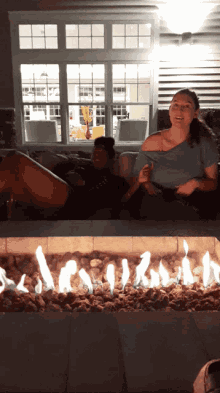 two women sitting in front of a fire pit with one wearing a shirt that says ' i 'm a ' on it