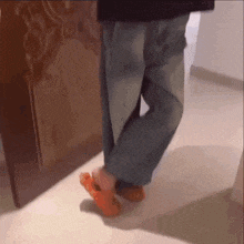 a person wearing a pair of orange crocs is walking on a tile floor .