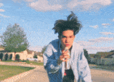 a young man in a blue jacket is drinking water from a plastic bottle