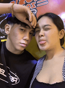 a man and woman sticking their tongues out in front of a sign that says yaja