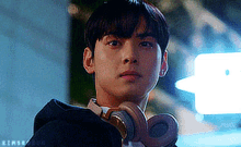 a young man wearing headphones is looking over his shoulder .