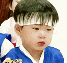 a young boy wearing a blue kimono and a headband .