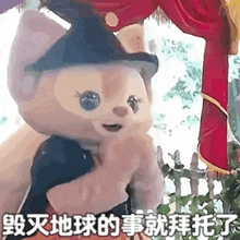 a teddy bear wearing a witch hat is holding a person .