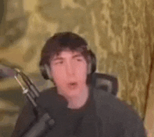 a man wearing headphones is sitting in front of a microphone and making a funny face .