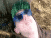 a man wearing sunglasses and a green hat