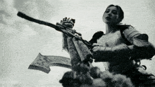 a black and white photo of a woman in armor holding a gun