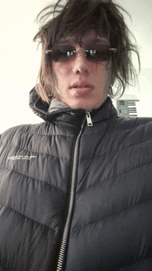 a person wearing sunglasses and a black jacket that says ' abercrombie & fitch ' on the front