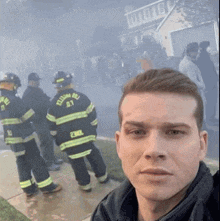 a man takes a selfie in front of a group of firefighters one of whom has the number 07 on their back