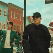 a man in a green suit and a man in a black jacket are walking down a city street .