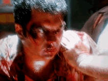 a man with blood on his face is being held by a woman .