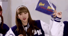 a girl in a blue and white jacket is holding a sign in her hand .