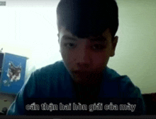 a young boy in a blue shirt is looking at the camera with a cat on his wall behind him .