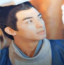 a close up of a man 's face with a hat on his head and a blue jacket .