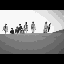 a black and white photo of a group of men walking in the desert .