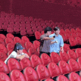 a group of people sitting in rows of red seats with the letter o on the back