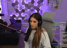a woman wearing headphones stands in front of a microphone with a purple wall behind her that says sunsettalks