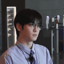a young man wearing glasses and a striped shirt and tie is looking at the camera .