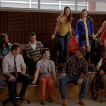 a group of people sitting and standing in a room with a man in a wheelchair