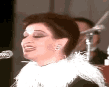 a woman is singing into a microphone while wearing a white fur collar
