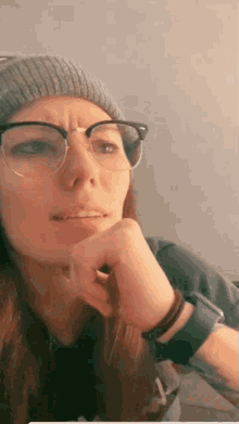 a woman wearing glasses and a hat is making a funny face .