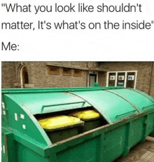 a green dumpster with two yellow trash cans inside of it is sitting in front of a brick building .