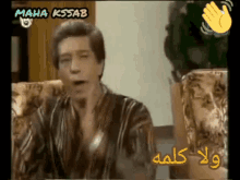 a man is sitting in a chair with the name maha kssab on the bottom right