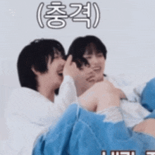 two boys are laying on a bed with a blue blanket and laughing .