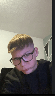 a young boy wearing glasses and a black sweater