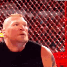 a man in a black tank top is standing in front of a chain link fence .