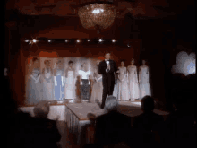 a man in a tuxedo stands in front of a group of women