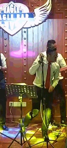 a man sings into a microphone in front of a sign that says eagle club