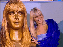 a woman in a blue dress is standing next to a gold statue of a woman