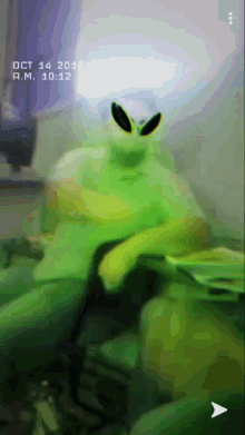 a person in a green alien costume sitting on a couch