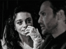 a man and a woman are sitting next to each other and the woman is crying while the man looks on .